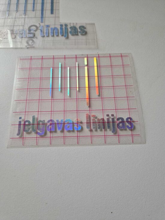 Automašīnas uzlīme ar biedrības logo ar spoguļa efektu, kas atstaro dažādās krāsās